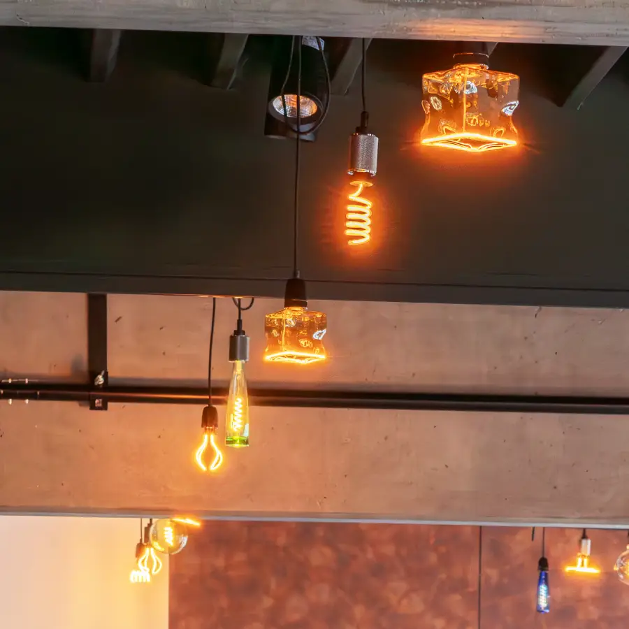 GlĂĽhbirnen an der Decke, die in Retro-Optik gestaltet sind und warmes Licht abgeben.