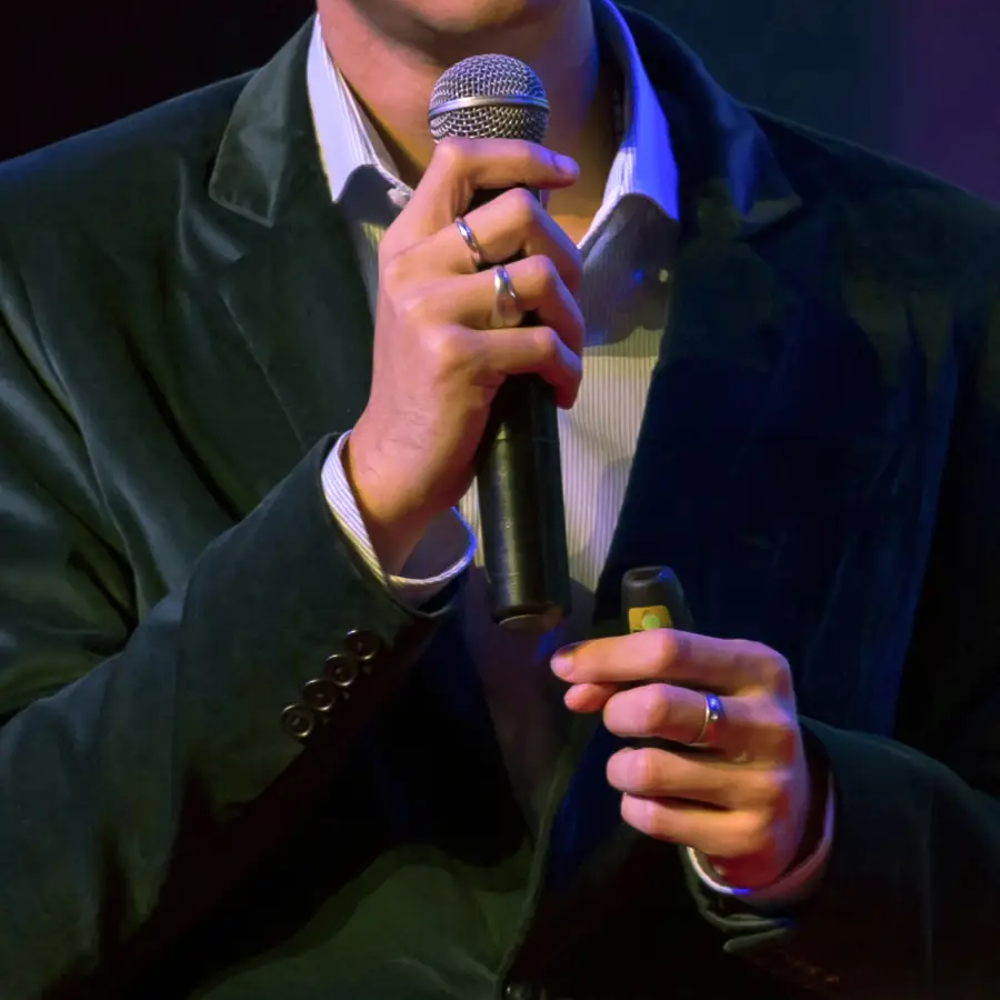 Ein Mann im Anzug hält ein Mikrofon in der Hand.