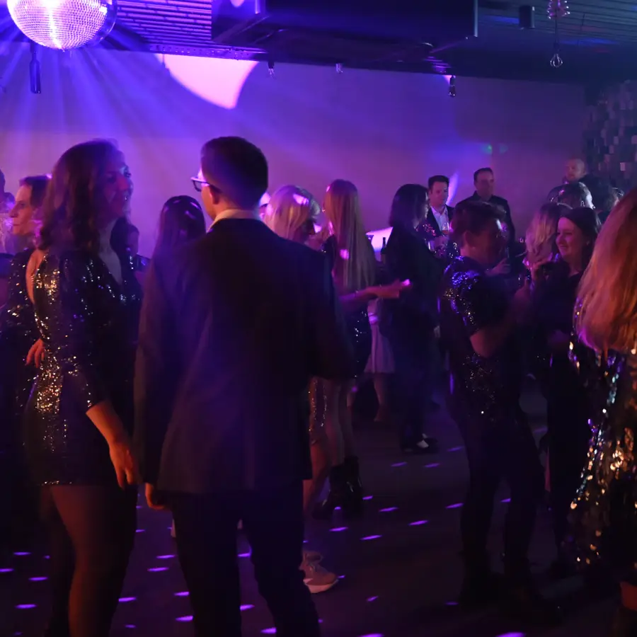 Voller Partyraum mit tanzenden Menschen und bunten Lichtern.